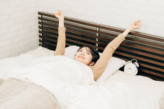 ベッドの中で伸びをする女性
