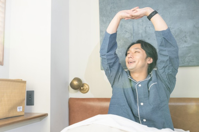 ベッドで伸びをする男性